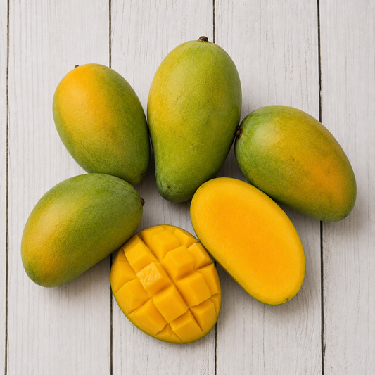 Six neelam mangoes arranged on a white wood plank surface, with four whole mangoes, one sliced open showing the yellow flesh, and one mango cut into cubes.
