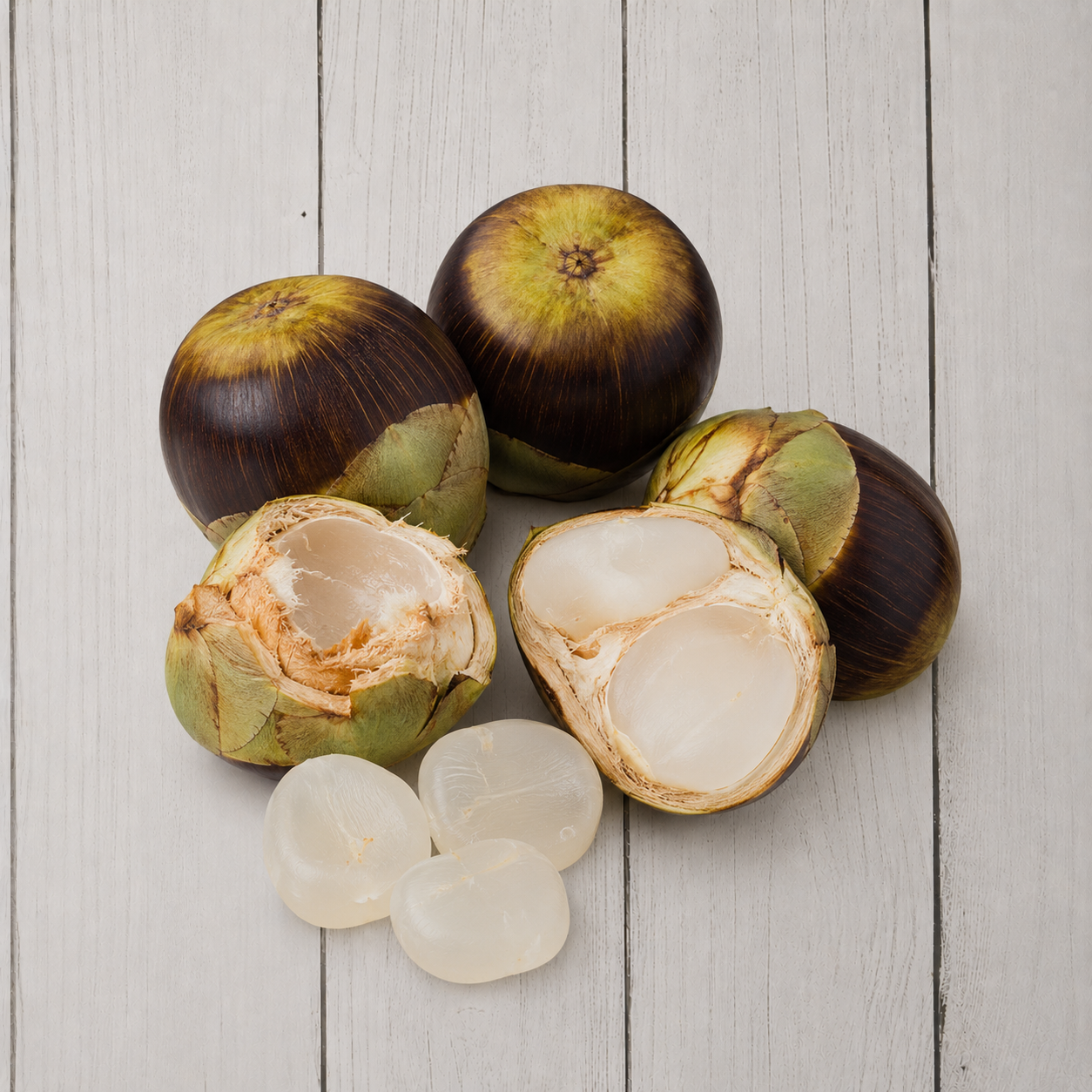 Several coconuts on a light gray wood plank background, with two coconuts whole and two halves showing the white flesh inside, plus four translucent white pearls in front.